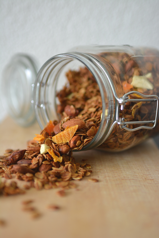 glass canister lying on its side, filled with a mixture of overflowing rolled oats and whole almonds
