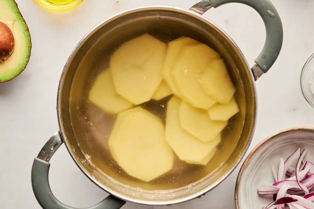 Boiling slices of potato in a stock pot.