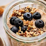 Breakfast Chia Pudding in a glass jar topped with fresh blueberries and pecans.