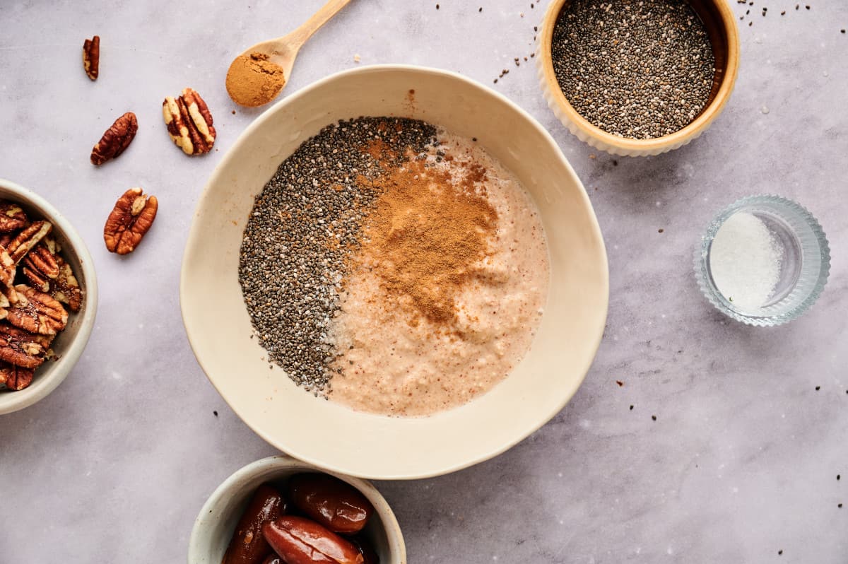 Chia seeds being mixed with blended dates and pecans with cinnamon.
