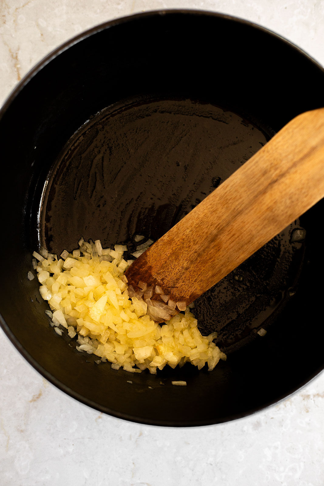 Cooking onion in a Dutch oven and stirring with a wooden spoon.