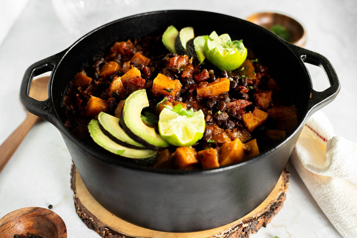 Black Bean and Butternut Squash Chili in a Dutch oven topped with Avocado and lime.