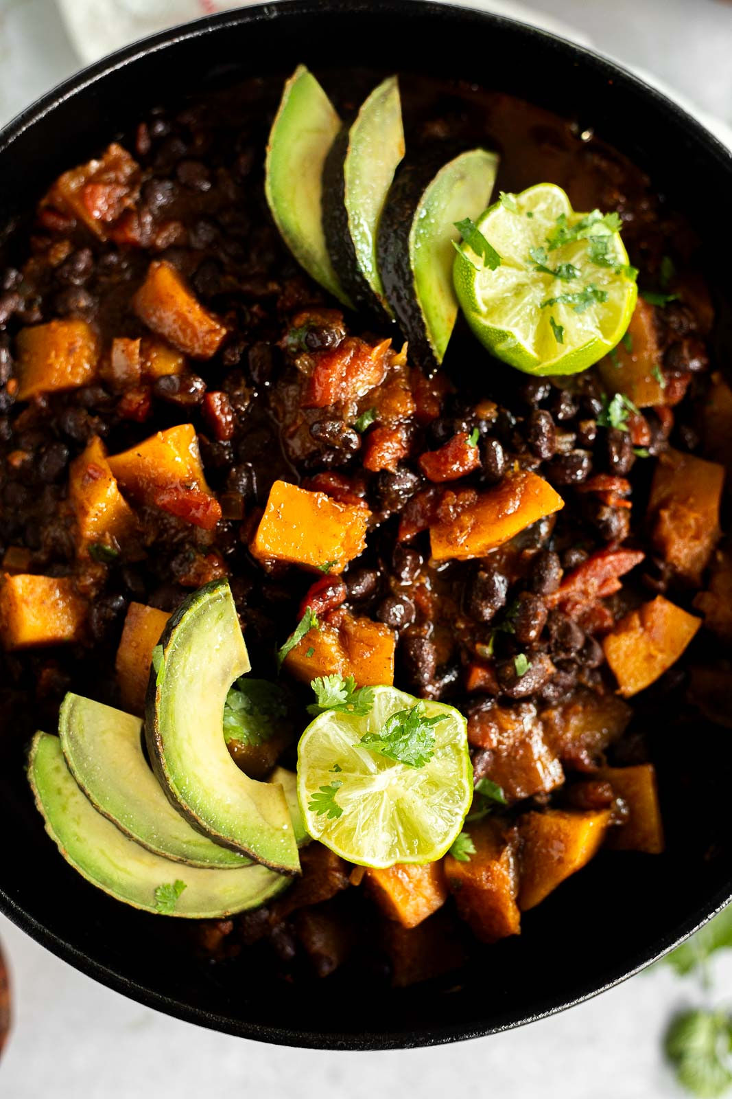 Black Bean and Butternut Squash Chili in a Dutch oven topped with Avocado and lime.