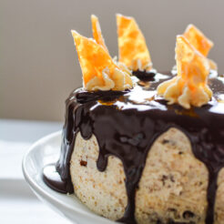 cropped half view image of a chocolate praline cake poured with ganache on top and and star shaped buttercream