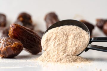 A spoon filled with date sugar is spilled over with dates in the background.
