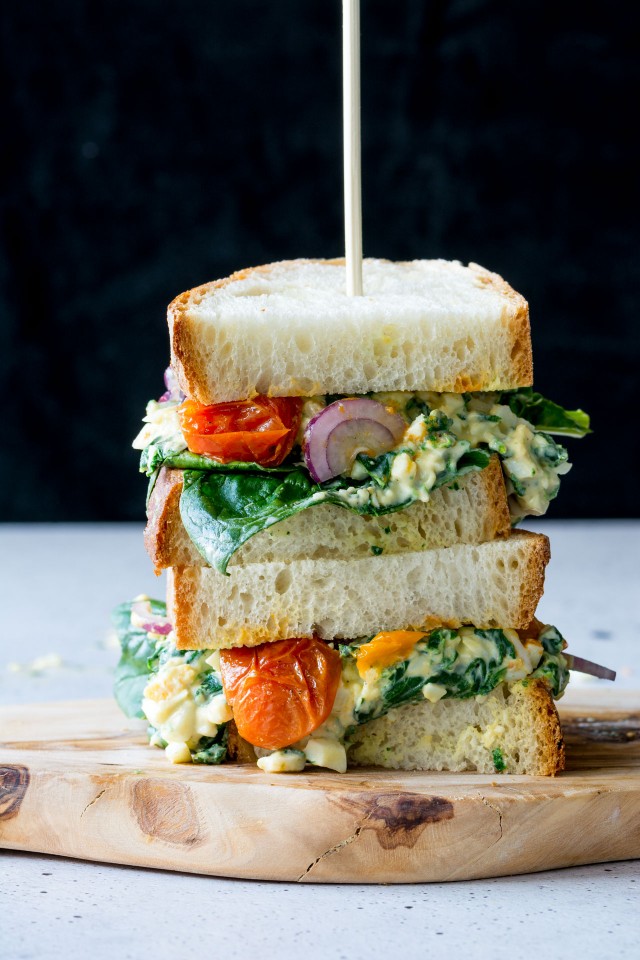 close up image of a delicious egg florentine sandwich with colorful roasted tomatoes