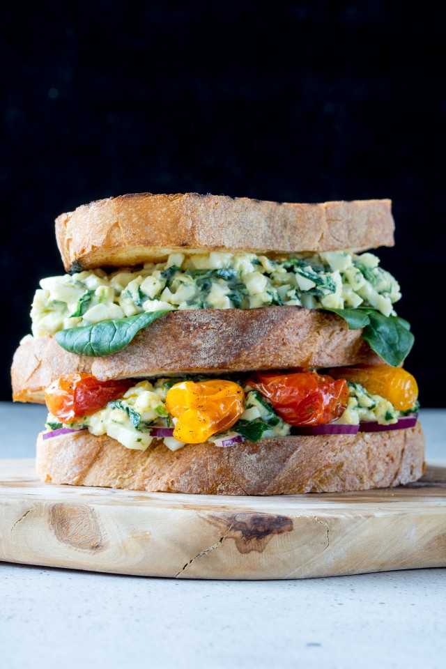 close up image of a delicious egg florentine sandwich with colorful roasted tomatoes