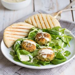 an image of homemade falafel in a plate topped with a creamy, and tahini dressing
