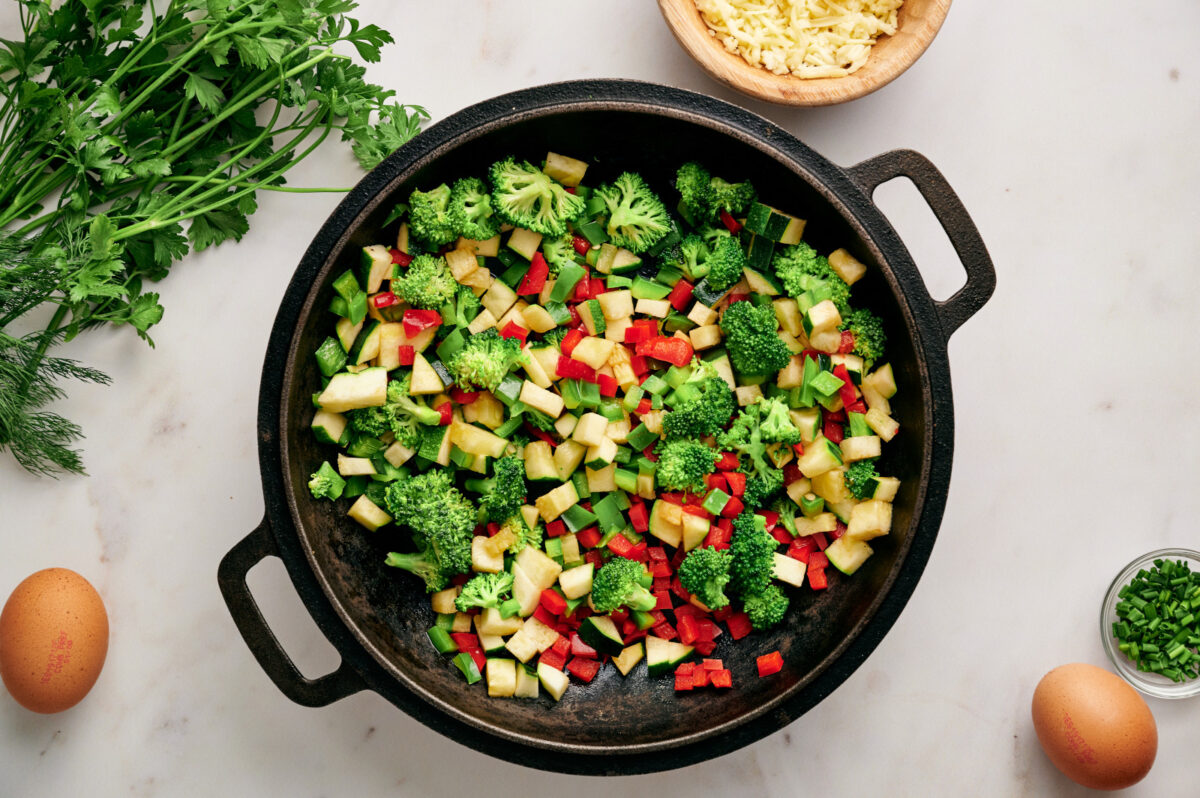 Zucchini, bell peppers, and broccoli florets in a cast iron skillet with olive oil.