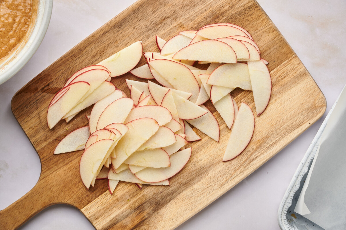 Thin sliced apples on a cutting board.