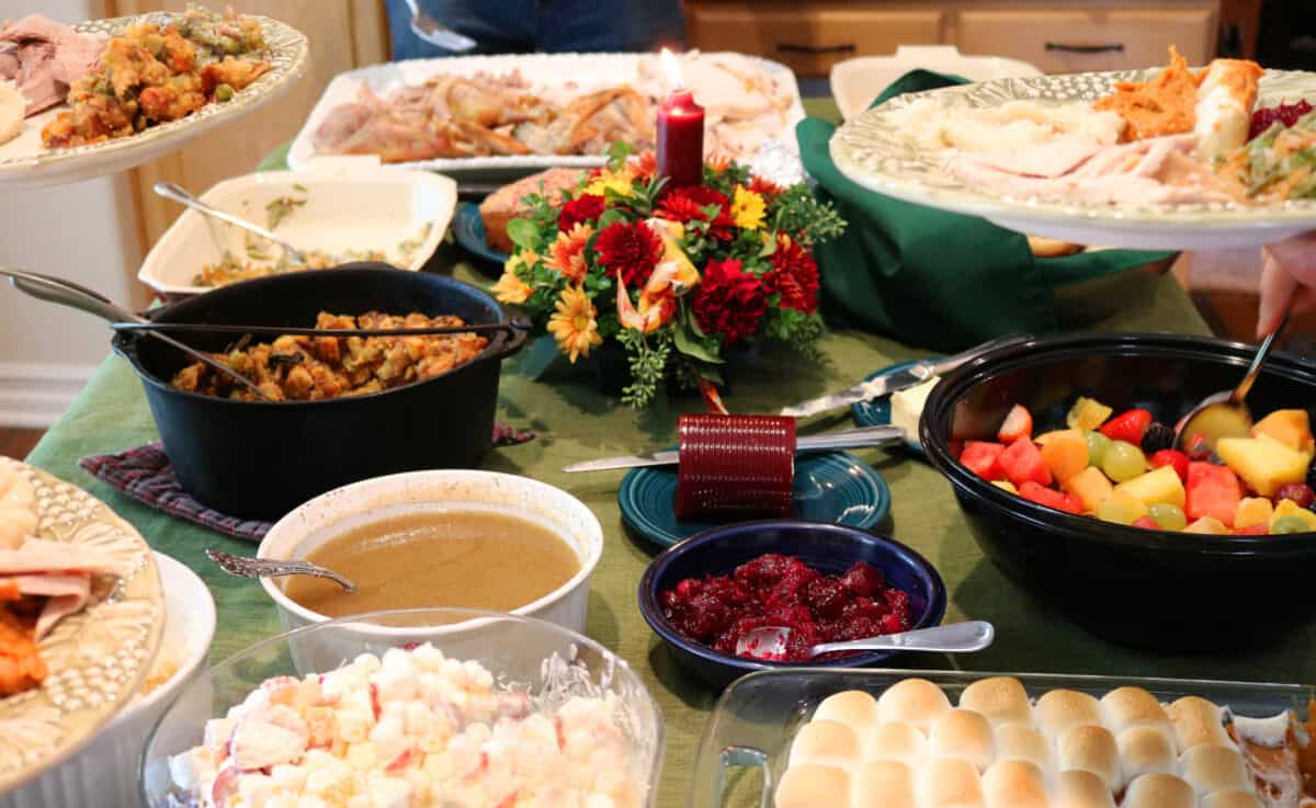 Casual holiday feast on a table with plates being filled.