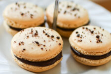 close-up image of four french macarons with a chocolate ganache filling, elegantly presented on a pastry plate
