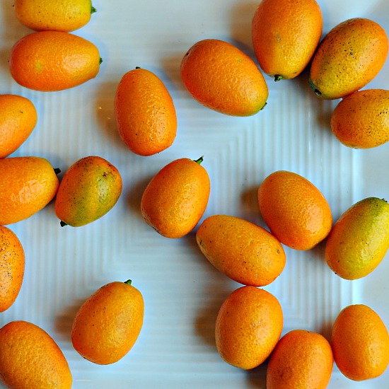 A group of kumquats on a white plate.