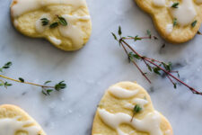overhead view of four lemon thyme and mint cookies with a drizzle of icing and garnished with fresh thyme leaves