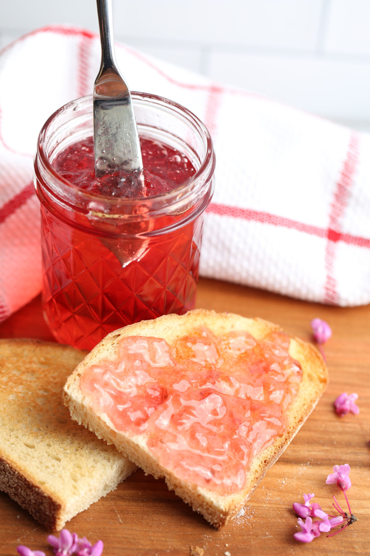 Redbud jelly in a jar with a piece of toast.