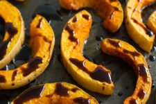 close up image of sliced roasted butternut squash drizzled with balsamic glaze
