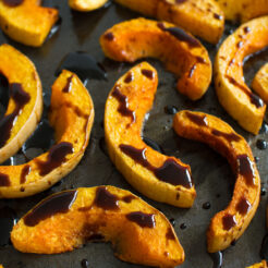 close up image of sliced roasted butternut squash drizzled with balsamic glaze