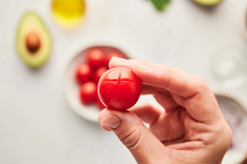 A cherry tomato that scored on the end with an X so the skin can be easily peeled.