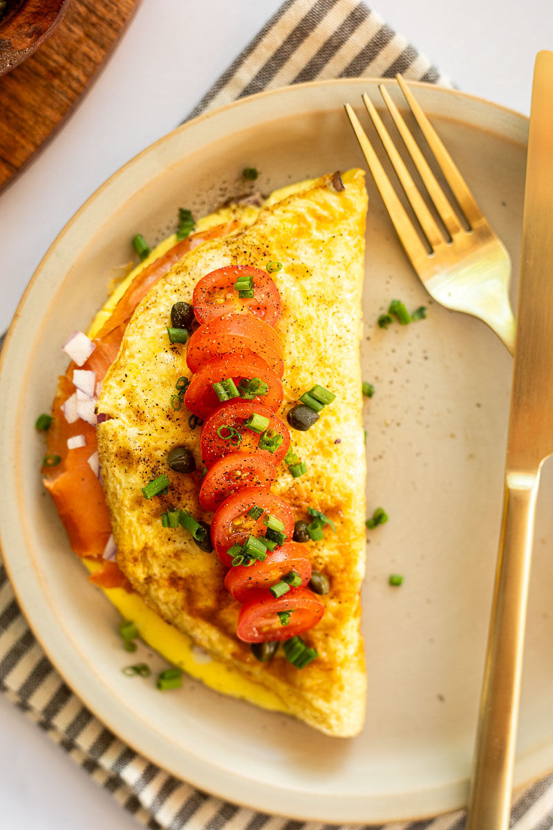 An overhead image of an omelet with fresh sliced tomates and garnished with chives.