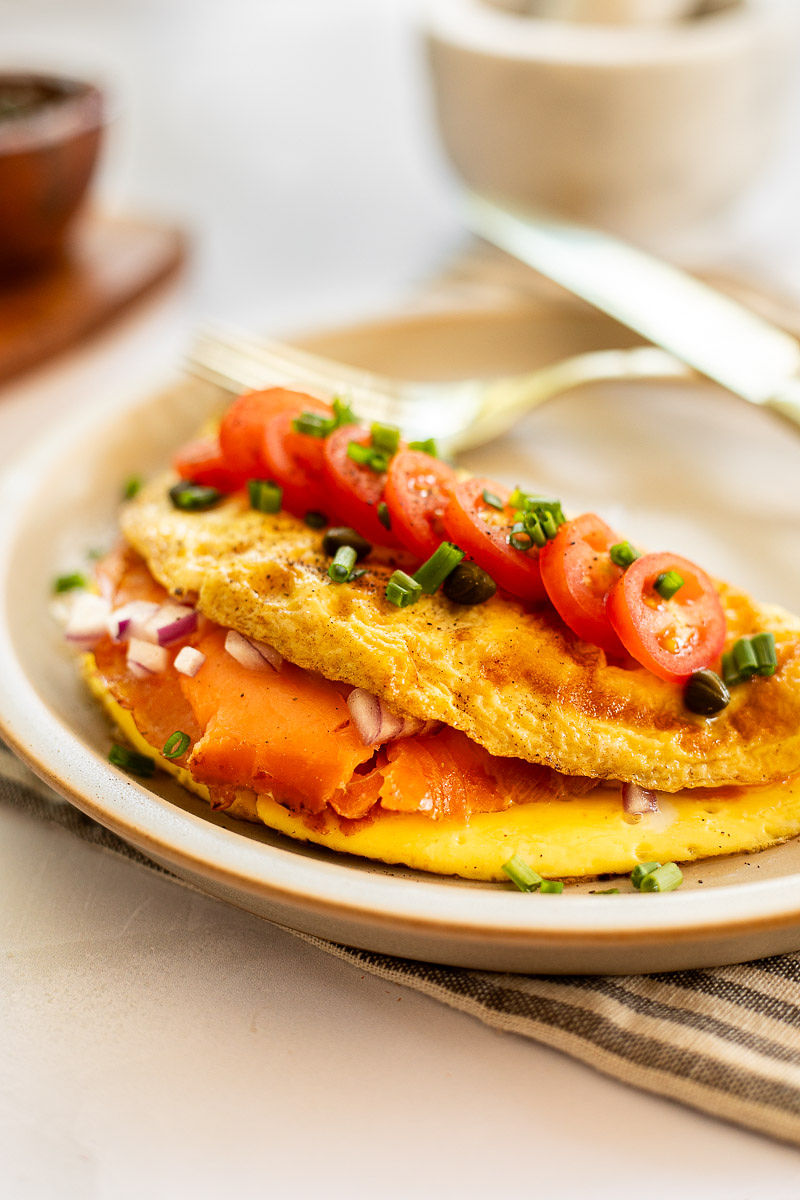 A smoked salmon omelet on a plate with a knife.