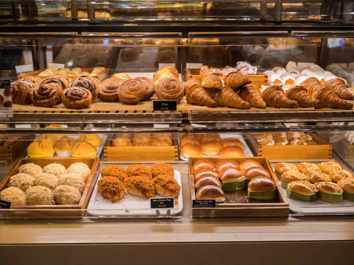 Assorted sugary pastries and breads arranged on tray selling at bakery shop.