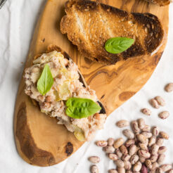 An image taken from above, showing white bean and artichoke crostini lying flat on the cutting board
